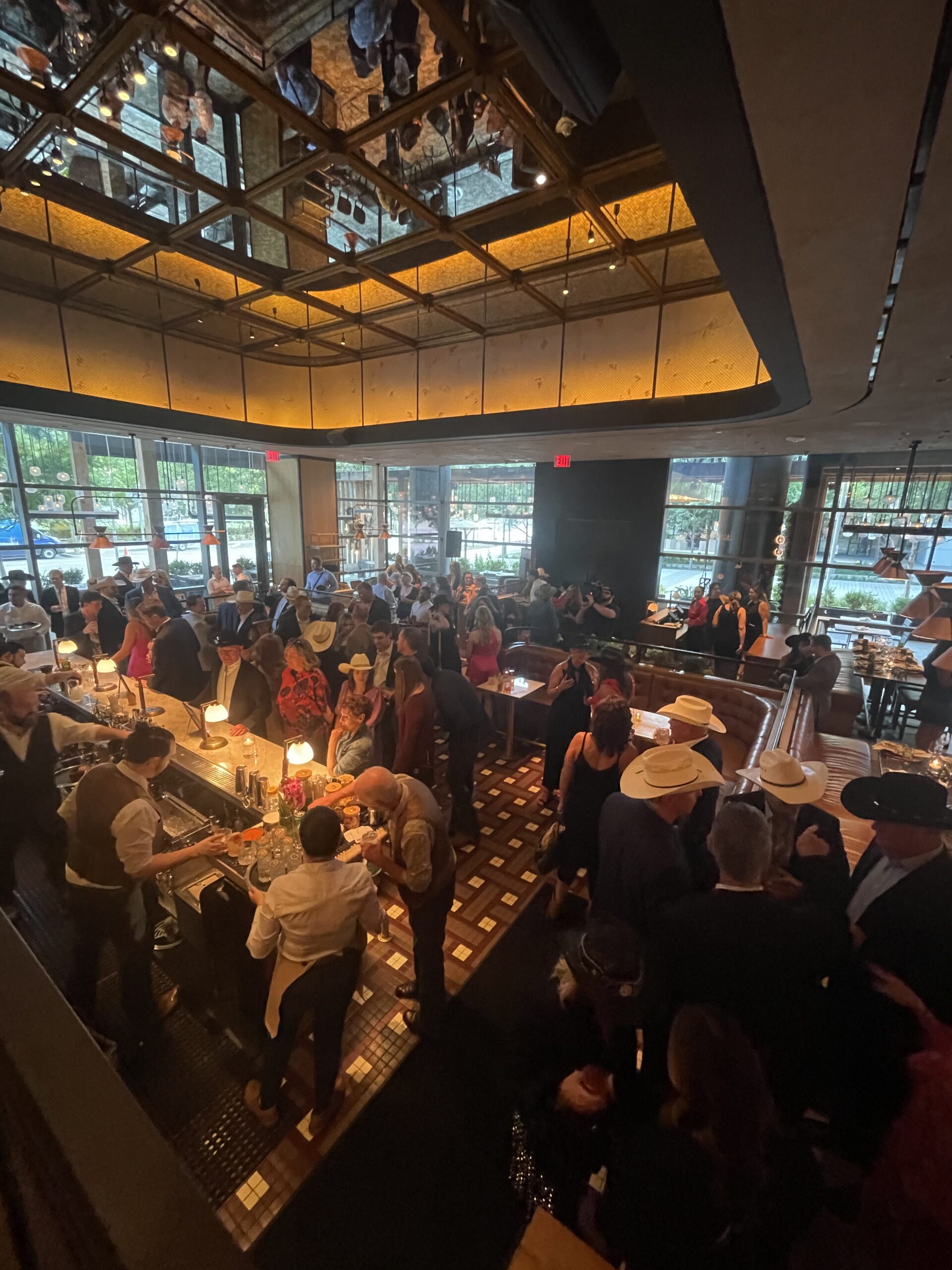 Guests filling a lively private event at a bar beneath a mirrored ceiling